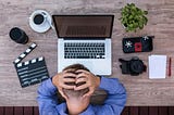 Man bows head in frustration over a laptop computer.