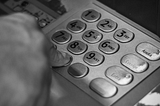 A black and white picture of someone pressing the buttons on an ATM.