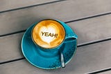 blue coffee mug on table with word YEAH!