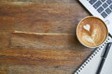 Coffee cup with heart in froth on wooden desk