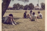 Group of teenage boys in 1980s Australia. One sits off to the side with his head between his knees.