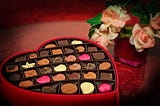 An image of Valentine's Day chocolates and pink roses.