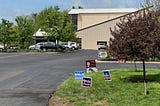 Picture of polling place parking lot with political signs.