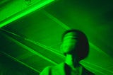 Person with a blurred face in a garage, the entire picture is saturated with emerald green