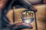 An out-of-focus hand holding a small, in-focus crystal ball