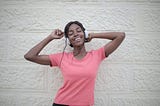 Woman in pink shirt with headphones on dancing to the music