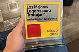 An unseen GrainChain team member holds our glass award, which says “Los Mejores Lugares para Trabajar en la Region Occidente,” Great Place to Work, and Mexico 2023.