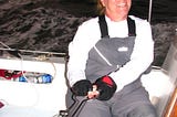 Dianne A Allen at the helm of a sailing yacht racing at sea.