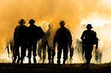 Silhouettes of army soldiers in the fog against a sunset, marines team in action, surrounded fire and smoke, shooting with assault rifle and machine gun, attacking enemy