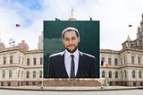 headshot of marte with a photo of NYC’s city hall in the background.