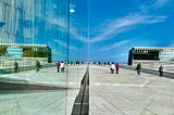 A wide view of the Oslo Opera House, showing the reflections on the glass surfaces.