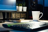 A desk with a computer, keyboard, cup and the logo “No Bad Days”.