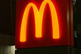 The golden arches of a McDonalds logo, shining out from a red background.