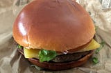 A cheeseburger sitting on a brown wrapper
