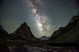 Snowcapped mountains at night time with vivid white starlight connecting the sky and the earth in a Milky Way band