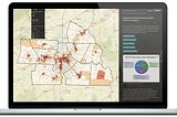 Photograph of a data dashboard that includes a map of counties, a pie chart, and text too small to read