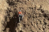 Climber ascends a rugged rock face, showcasing determination and skill.