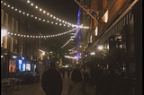 A couple walking on streets surrounded by lights