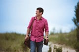 Man walking happily on boardwalk with saddle bag and book. A step by step guide to knowing if you’re an asshole for PodMen.