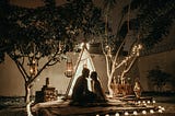 Man & woman in romantic setting, tent, lights and nature