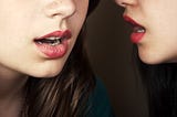 Women with red lipstick gossip together.