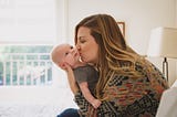 A photo of Chelsey Glasson holding and kissing her baby.