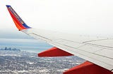 Photograph depicting a view from a Southwest Airlines plane looking over a city during winter