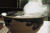 close-up bowl of hot rice back-lit to show rising steam