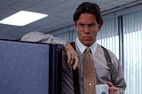 Gary Cole as Bill Lumberg, the evil, dolt of a supervisor in Office Space. He is holding a coffee mug, dressed like a chud in business casual, and leering at the camera with his glasses.