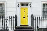 Yellow door to an all white apartment building