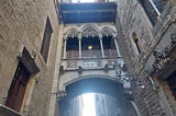 An ornate Gothic pedestrian bridge between two buildings in Barcelona.