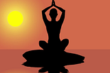 A silohuette of a person in yoga’s lotus pose, with the sun setting in the background