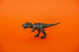 Scrum Masters: You don’t have to have the same fate as the dinosaurs (T-Rex toy on orange background) | Photo by Cup of Couple on Pexels