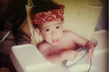 me as a baby in a highchair with a bandana. appox age 2