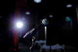 A microphone set up on stage with a spotlight.