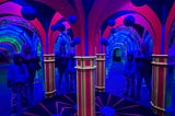 Me and my kiddo at the Infinite Mirror Maze on Pier 39, looking in many mirrors with lots of black-light arches and mirrors!