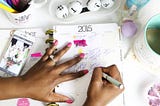 Mãos de uma mulher negra escrevendo em uma agenda em 2015.