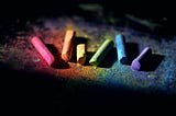 A rainbow of coloured chalk against a black background