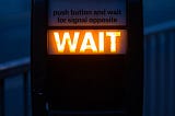 WAIT appears as a pedestrian illuminated sign