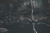 A man on a balance rope walking across a gorge