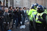 Group of protesters stand facing group of armoured police