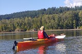 Person kayaking on lake with mountains behind