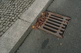 from the top, angled, looking at a drain at the side of a street