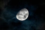 A captivating view of the gibbous moon shining through dark clouds in the night sky over Rio de Janeiro.