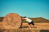 Man pushing hay bale, get rid of wrong mindset and become an achiever