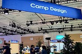 Wide shot of the Camp Design “booth” during TDX at Moscone Center. A large blue Camp Design banner hangs from the ceiling.