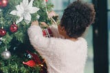 African American child decorating a Christmas tree.