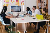 Team sitting at a desk looking at a screen