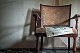 A newspaper left on an easy chair in a now-abandoned house.