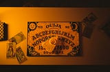 A classic Ouija board, with three Tarot cards on the side